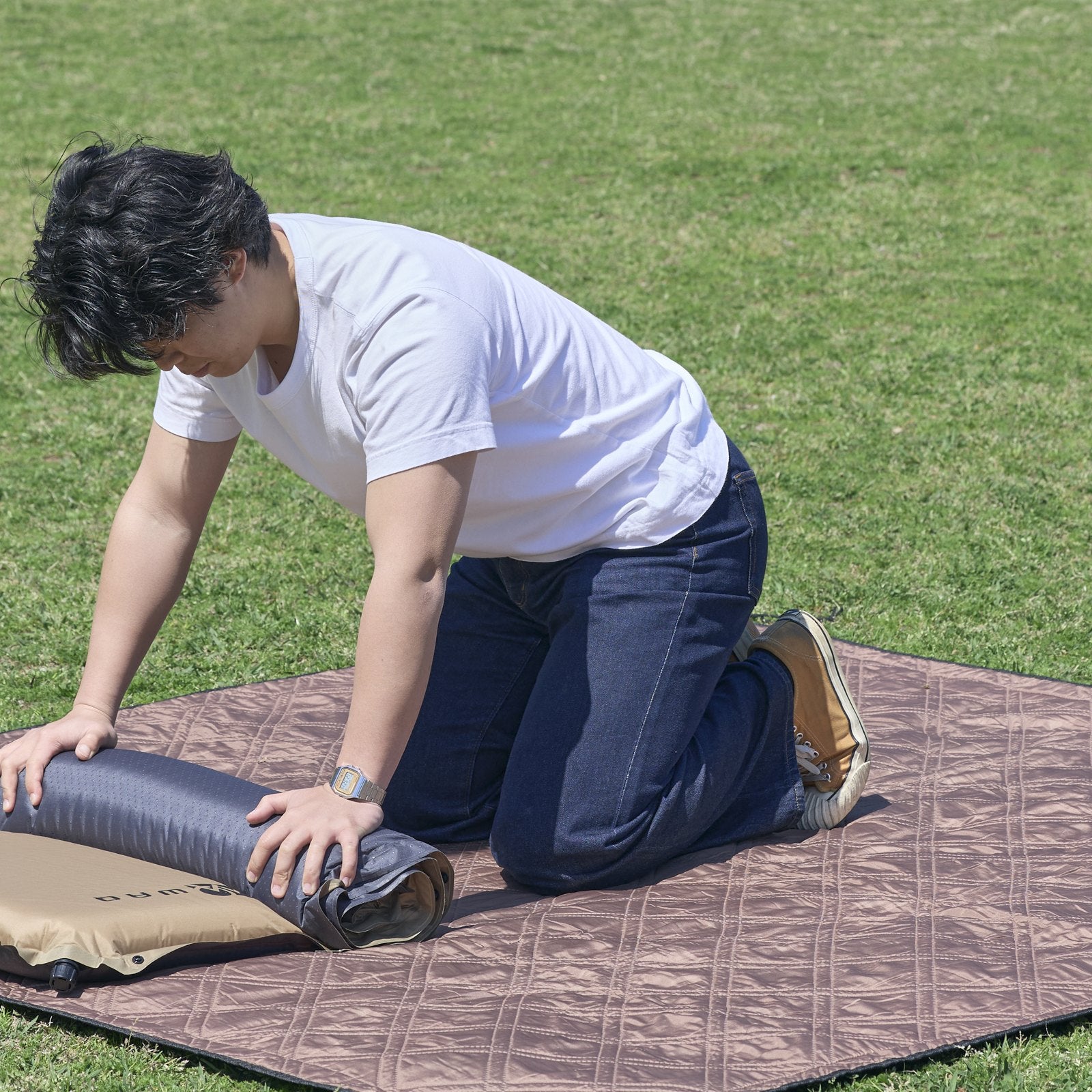 膝をつき、体重をかけてインフレーターマットを丸めている様子