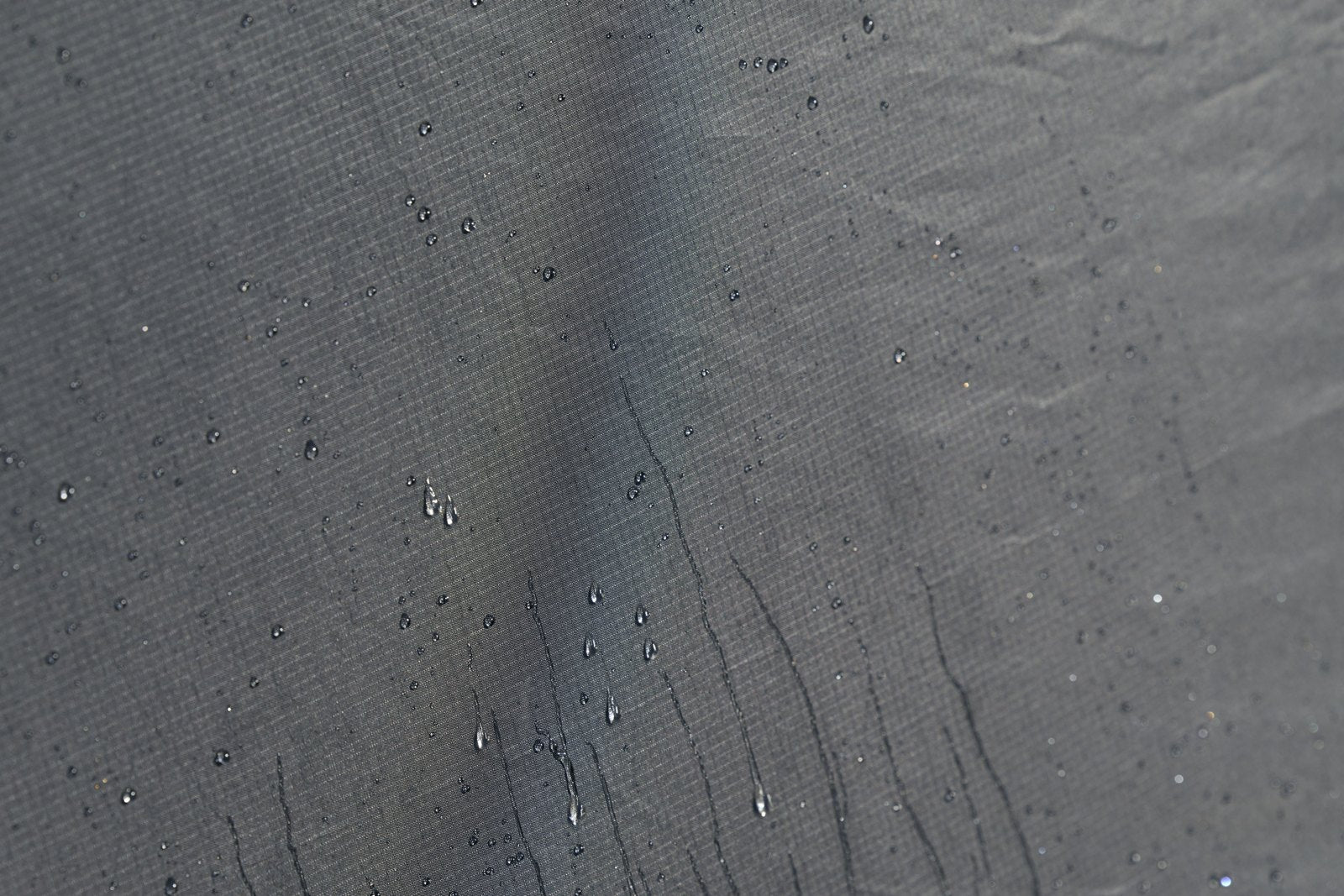 黒い生地の表面に、水滴が玉になって付いている接写